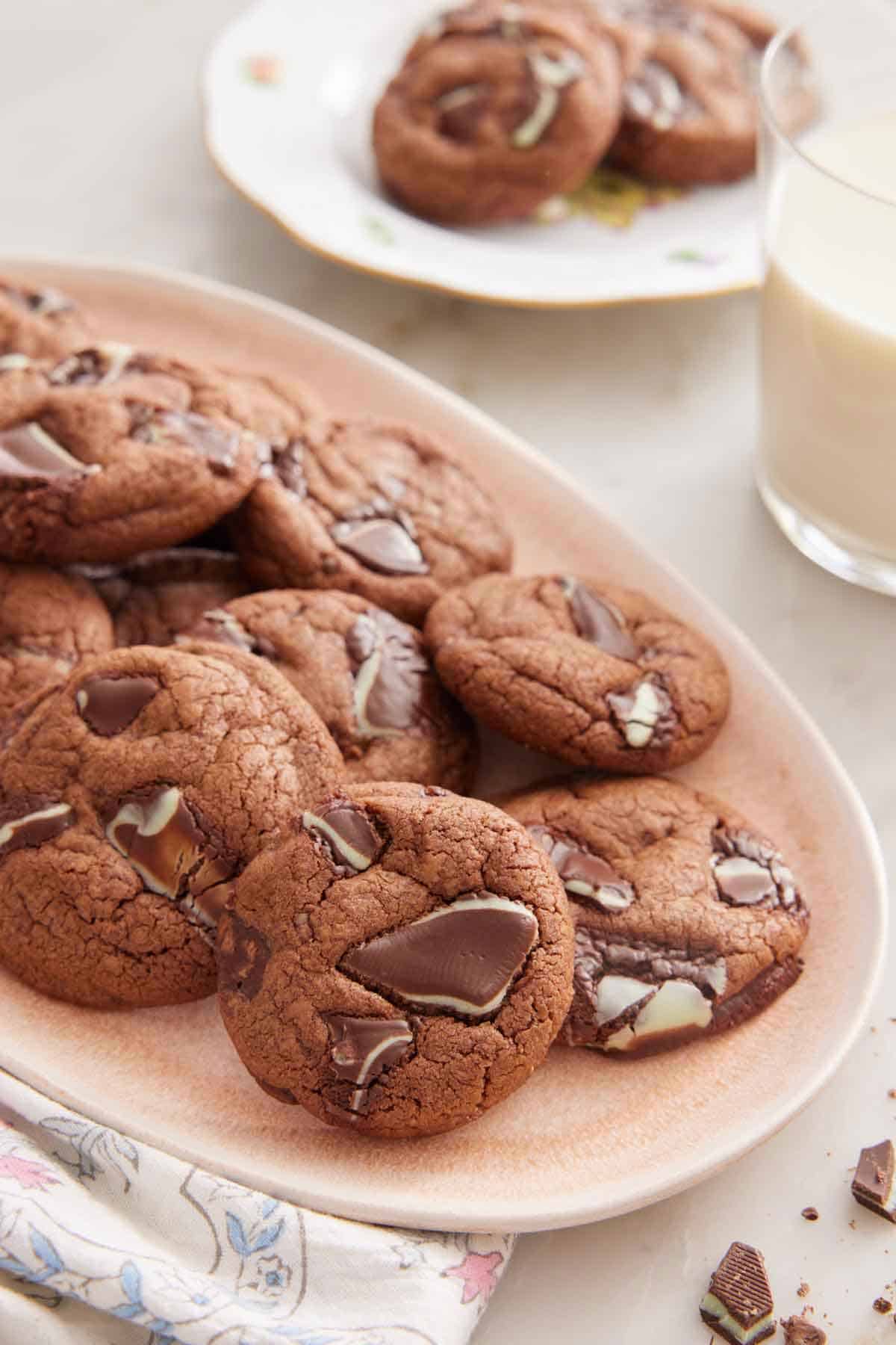 A platter of Andes Mint Cookies with a glass of milk and plate of cookies in the background.