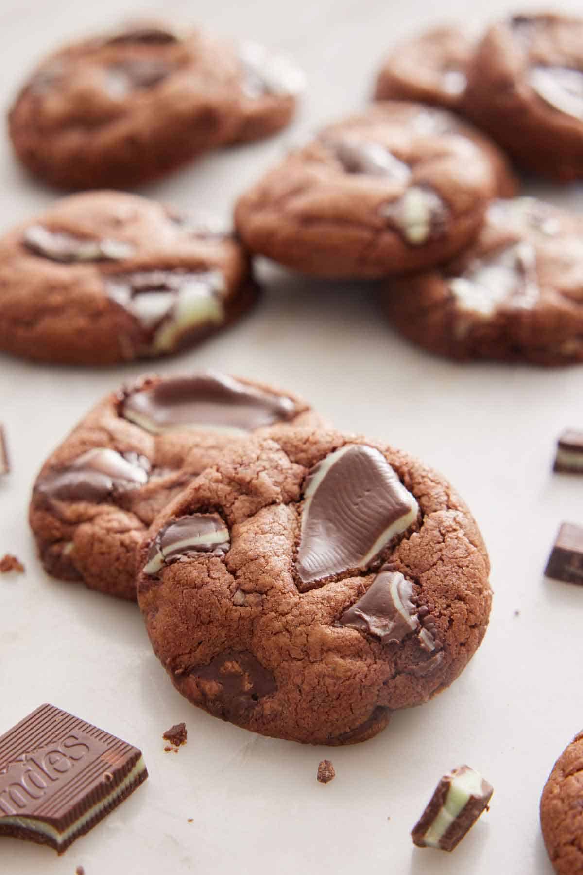 Multiple Andes Mint Cookies on a surface with chocolate bits scattered around.