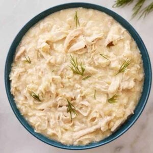 Overhead view of a bowl of avgolemono with dill on top.