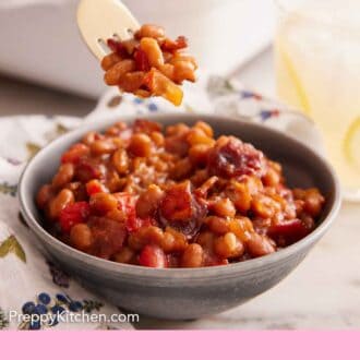 Pinterest graphic of a forkful of baked beans lifted from a bowl with a baking dish in the background.