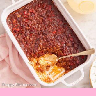 Pinterest graphic of an overhead view of a baking dish with baked beans with a serving scooped out with the spoon still inside. Lemonade and glasses off to the side.