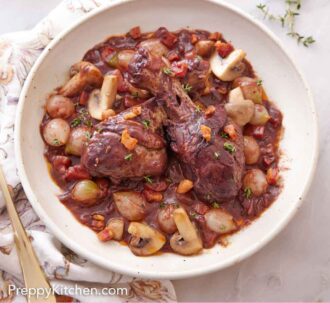 Pinterest graphic of a plate with a serving of coq au vin with torn bread in the back.