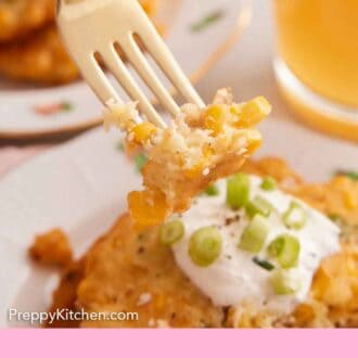 Pinterest graphic of a fork lifting up a bite of corn fritters from a plate of fritters topped with sour cream and green onions.