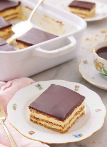 A plate with a slice of éclair cake with a baking dish in the background.