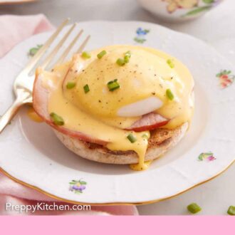 Pinterest graphic of eggs benedict on a plate with hollandaise sauce and chives on top. A fork beside it.