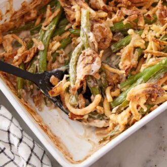 Overhead view of a baking dish of green bean casserole with a serving removed and with a serving spoon tucked in.