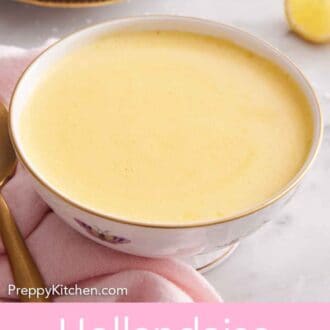 Pinterest graphic of a bowl of hollandaise sauce with lemon wedges and asparagus in the background.