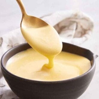 A bowl of hollandaise sauce with a spoonful lfited.