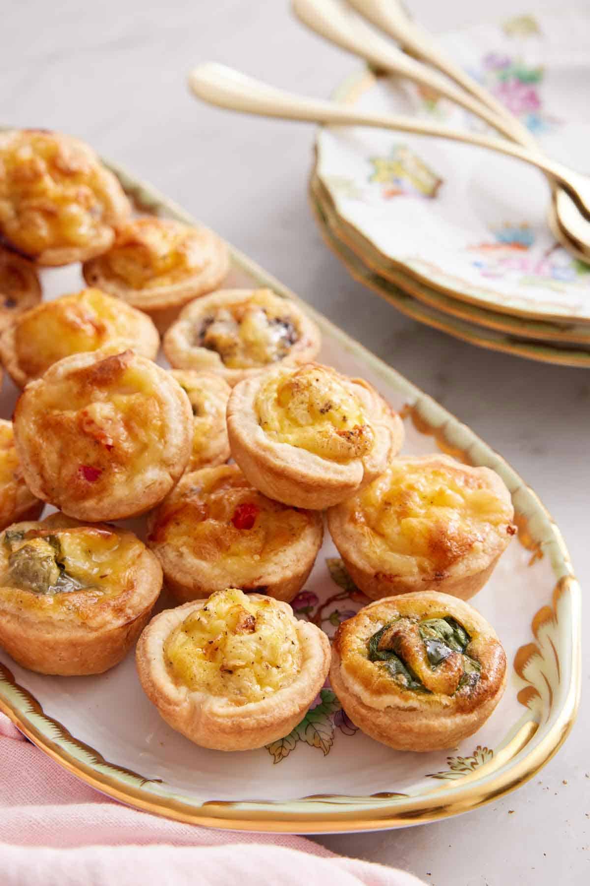 A platter of mini quiche with an assortment of fillings.