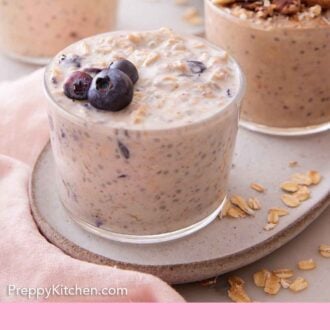 Pinterest graphic of a platter with a glass of overnight oats topped with blueberries with additional glasses in the background with different toppings.