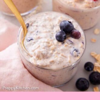 Pinterest graphic of a spoon inside of a jar of overnight oats with blueberries.