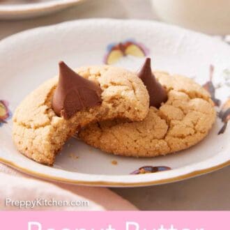 Pinterest graphic of a plate with two peanut butter blossoms. One has a bite taken out of it.