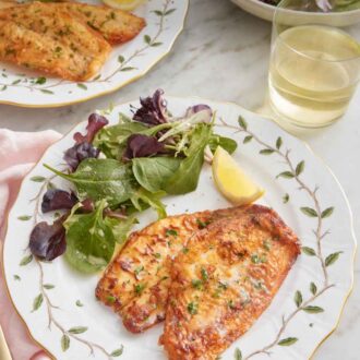Pinterest graphic of two plates of sole meunière with a handful of mixed greens and a lemon wedge.