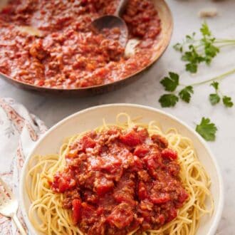 Pinterest graphic of a bowl of noodles with spaghetti sauce on top with a skillet full of sauce in the background.