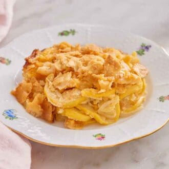 A plate of squash casserole with a pink napkin on the side.