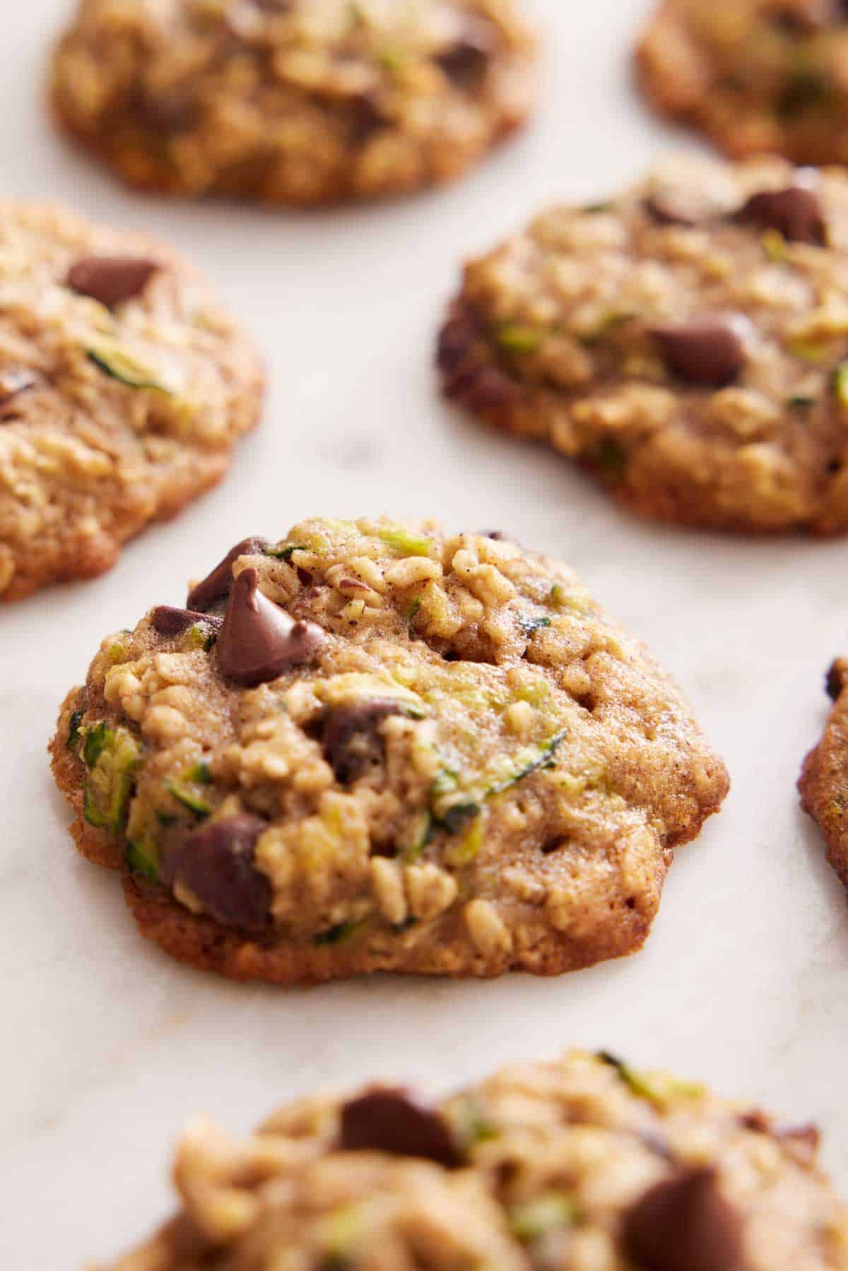 Multiple zucchini cookies on a flat surface with one cookie in focus.