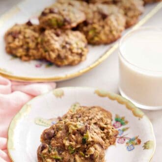 Pinterest graphic of a plate with two zucchini cookies with a glass of milk and platter of more cookies in the background.