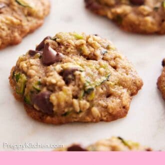 Pinterest graphic of multiple zucchini cookies on a flat surface with one cookie in focus.