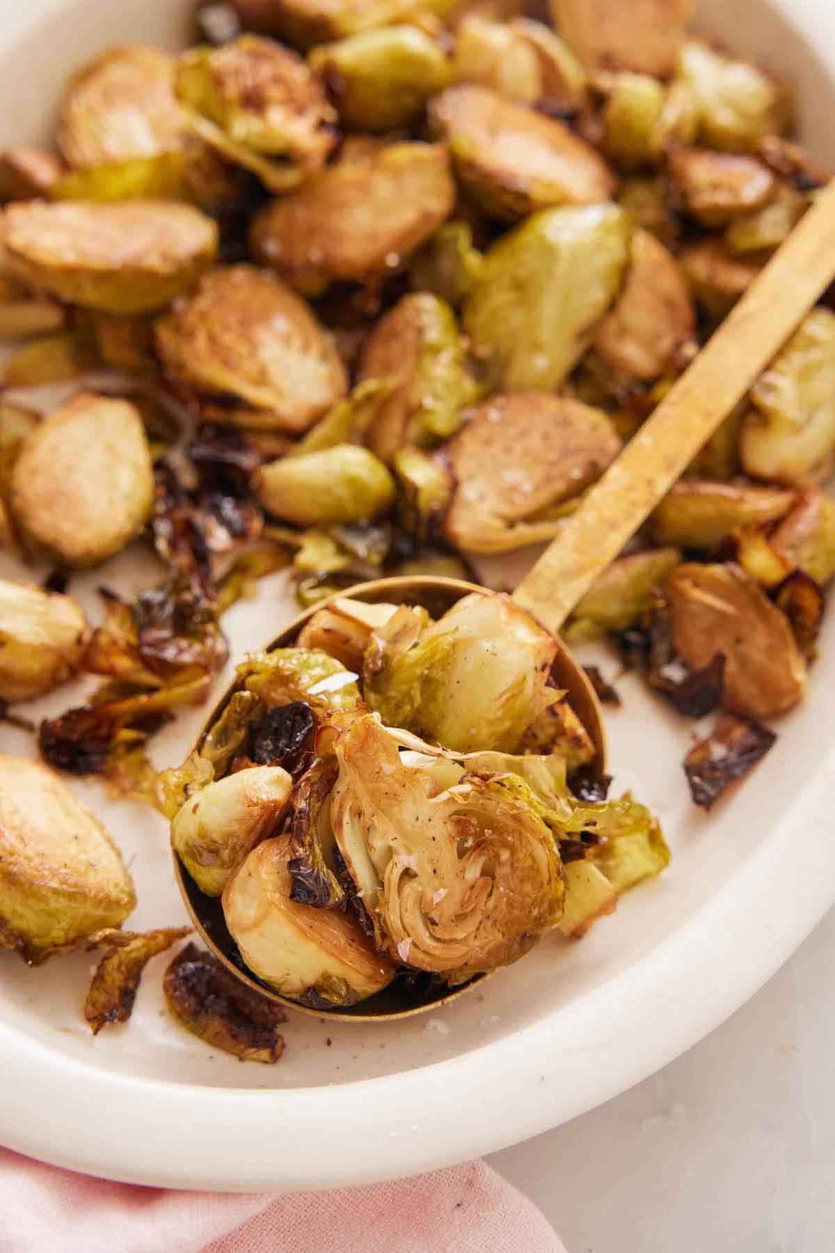 A platter of air fryer Brussels sprouts with a serving spoon inside.