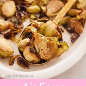 Pinterest graphic of a platter of air fryer Brussels sprouts with a serving spoon inside.