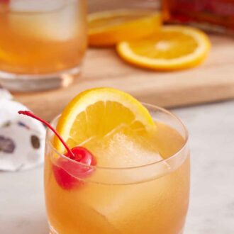 Pinterest graphic of a glass of Amaretto Sour with a second one in the background along with orange slices.