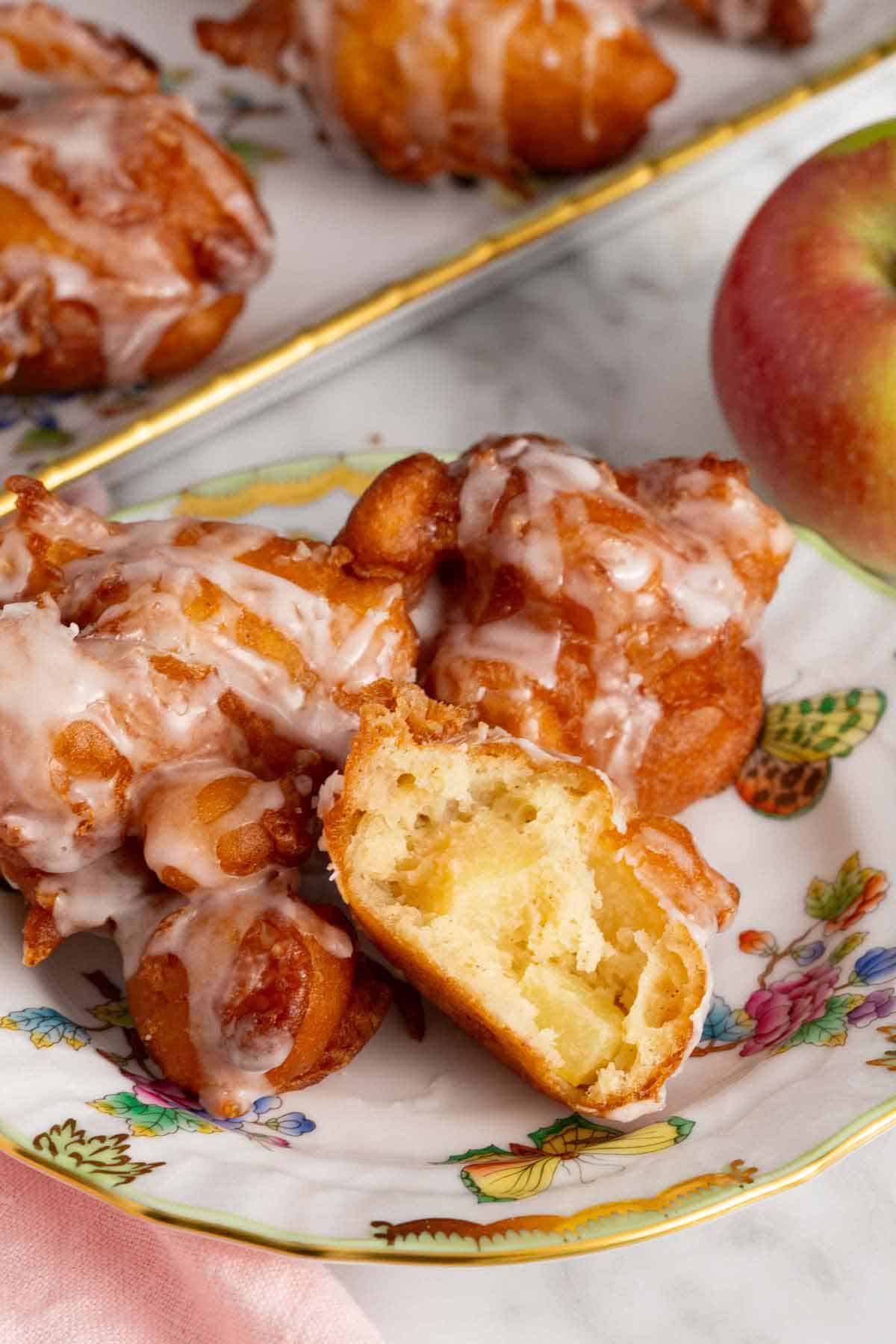 A plate of apple fritters with one cut open, showing the interior.