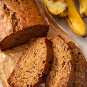 Pinterest graphic of a loaf of banana bread with three slices in front. Bananas in the background.