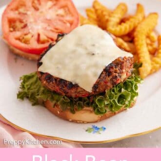 Pinterest graphic of a plate with a black bean burger with a slice of melted cheese on top with the burger bun with a tomato slice in the background.