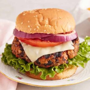 A plate with a black bean burger with some fries in the background.
