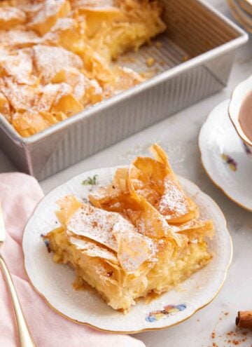 A plate with a serving of Bougatsa and the baking pan with the rest in the background.