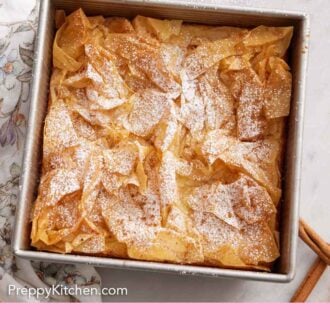 Pinterest graphic of an overhead view of a square pan of Bougatsa with a sifter of powdered sugar to the side.