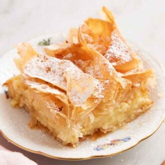 A plate with a serving of Bougatsa with cinnamon sticks to the side.
