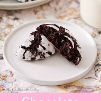 Pinterest graphic of a small plate with one chocolate crinkle cookie broken in half. One half stacked on the other, showing the cookie's interior.