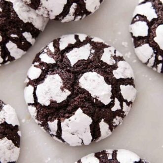 Overhead view of chocolate crinkle cookies on a flat surface.
