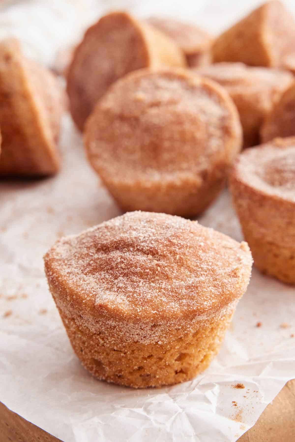 A cinnamon muffin on a parchment paper with more in the background.