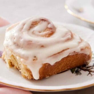A plate with a serving of cinnamon roll with glaze on top.