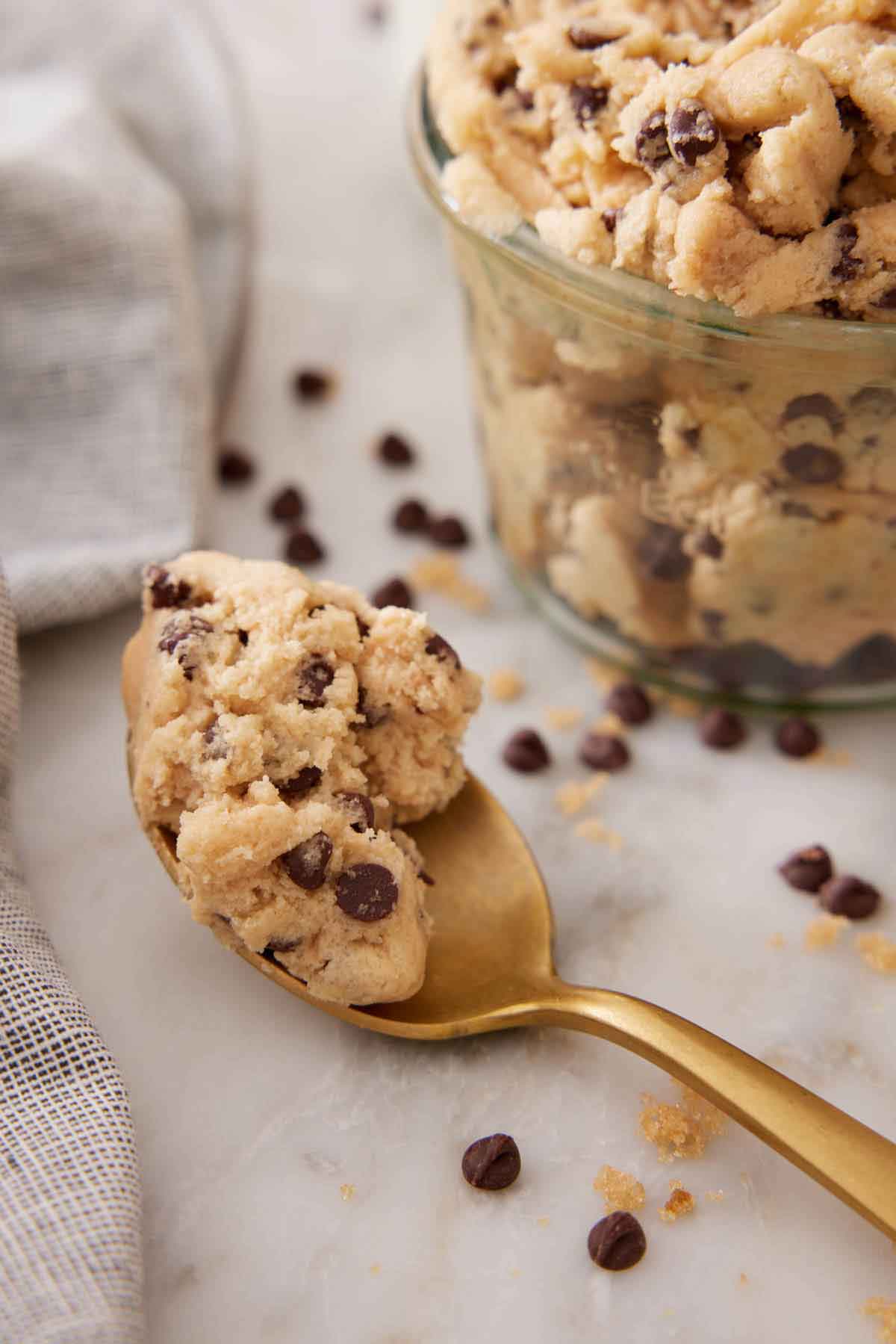 A spoonful of edible cookie dough beside a container.