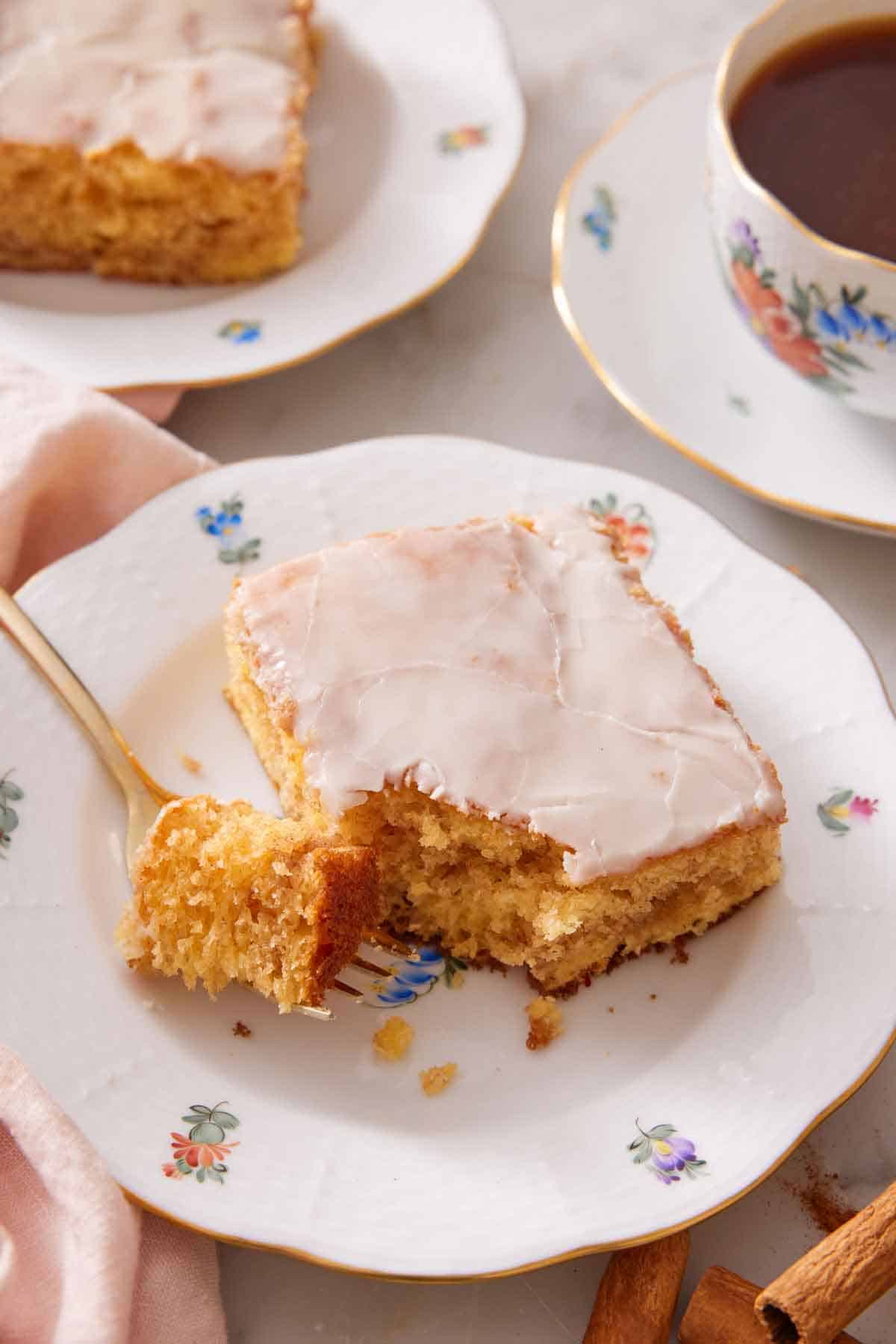 A plate with a slice of honey bun cake with the corner bite on a fork.