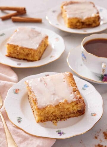 Three plates with sliced honey bun cake with a cup of coffee to the side.