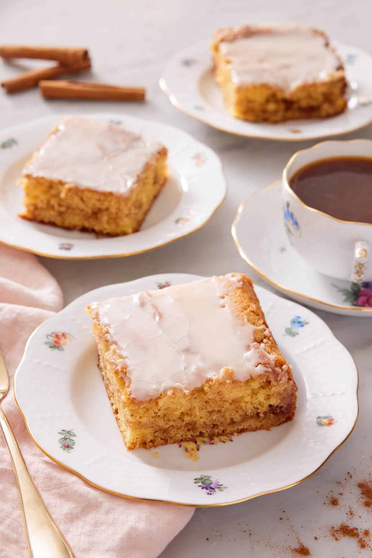 Three plates with sliced honey bun cake with a cup of coffee to the side.