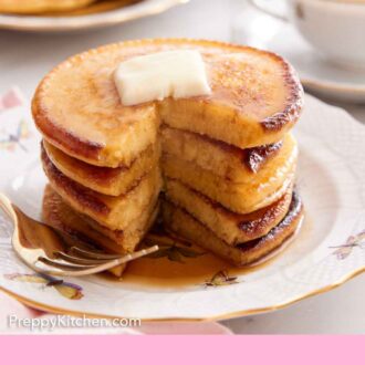 Pinterest graphic of a stack of Johnny cakes with a portion cut out. Butter on top.