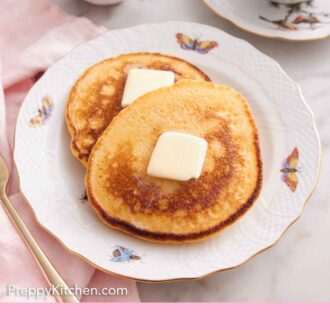 Pinterest graphic of a plate with two Johnny cakes with butter on each. Coffee and syrup in the background.