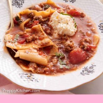 Pinterest graphic of a bowl of lasagna soup topped with cheese and basil ribbons.