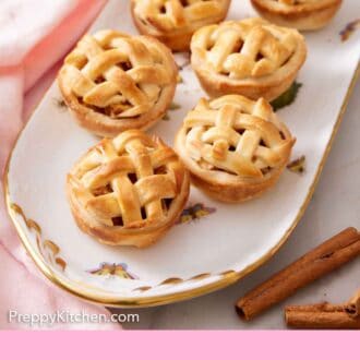 Pinterest graphic of a platter of mini apple pies with some cinnamon sticks on the side.