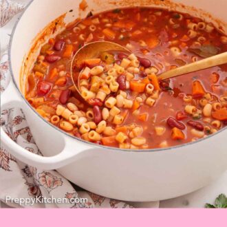 Pinterest graphic of a white pot of pasta fagioli with a ladle inside. Bowls and bread in the background.