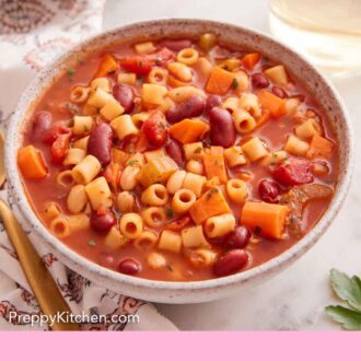 Pinterest graphic of a bowl of pasta fagioli with a glass of wine and second bowl in the background.