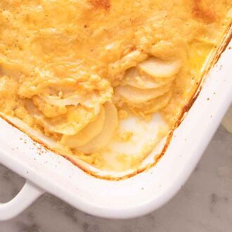 Overhead view of a casserole dish of potatoes au gratin with the corner serving scooped out.