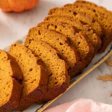 A platter with a loaf of pumpkin bread sliced.