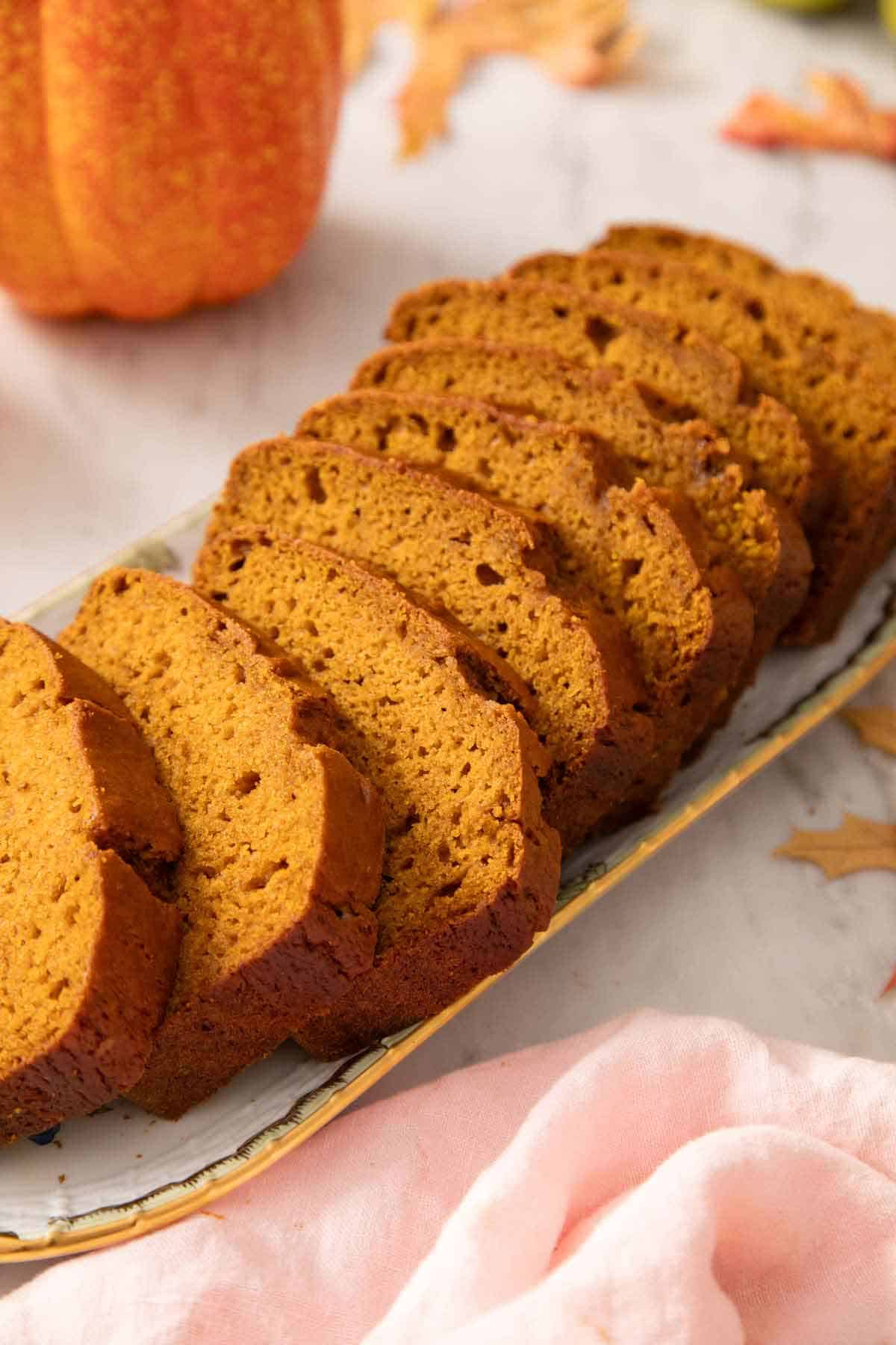 A platter with a loaf of pumpkin bread sliced.