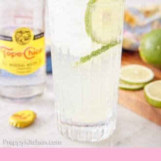 Pinterest graphic of a glass of ranch water with lime slices in the drink with a glass of topo chico in the background.